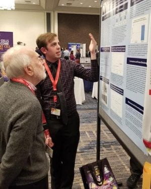 A student from the lab explains his research poster at a conference.
